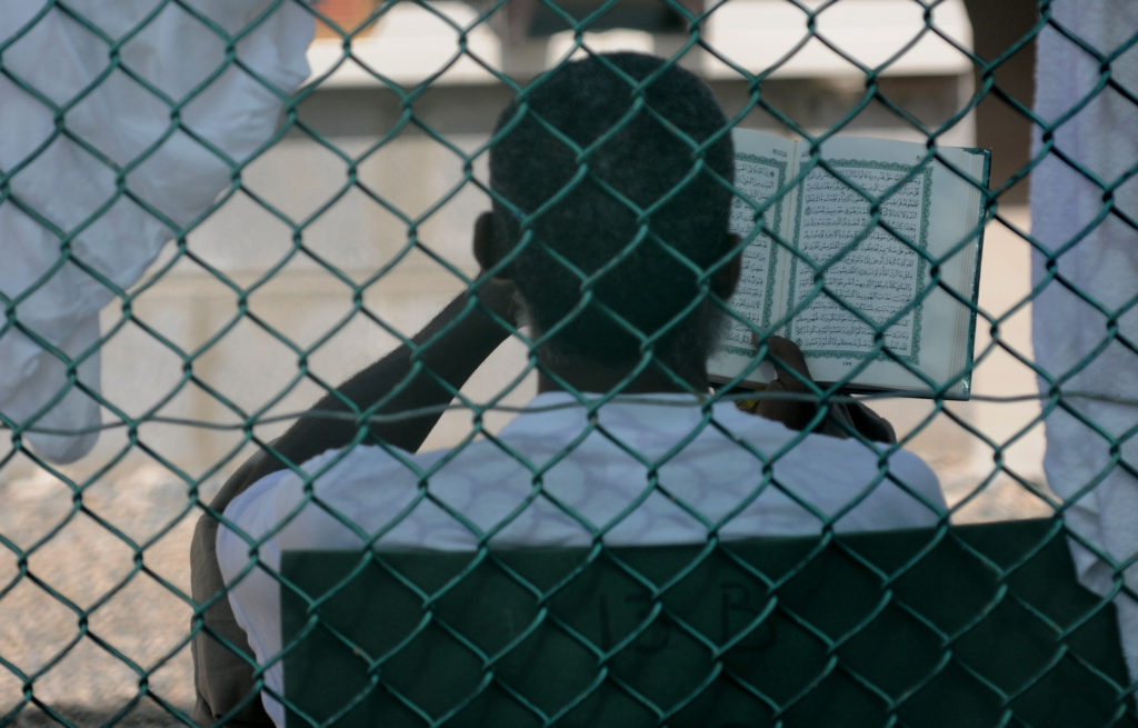 GUANTANAMO BAY, Cuba – A detainee reads the Qur’an in a recreation yard at Joint Task Force Guantanamo, June 8, 2010. Photo by Navy Mass Communication Specialist 3rd Class Joshua Nista.