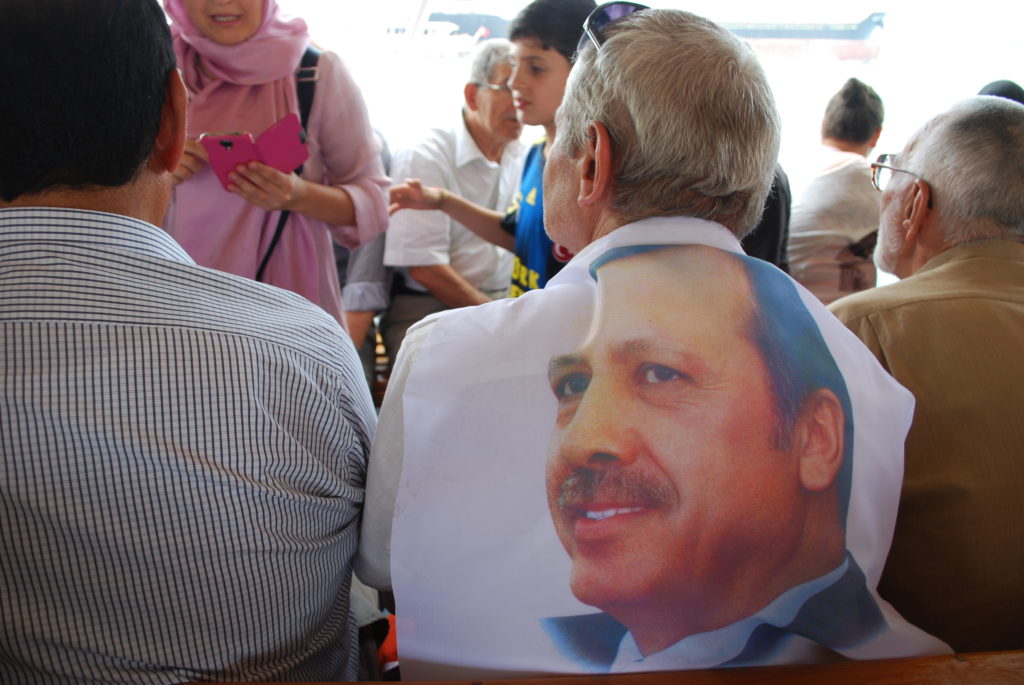 A supporter of the AKP drapes a photo of Erdoğan over his shoulders. Photo: Jenna Krajeski.