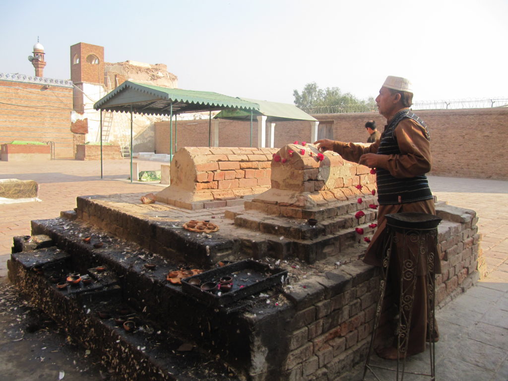 A man puts fresh garlands on the grave of a makhdoom at the shrine of Bahauddin Zakariya in the Multan fort.